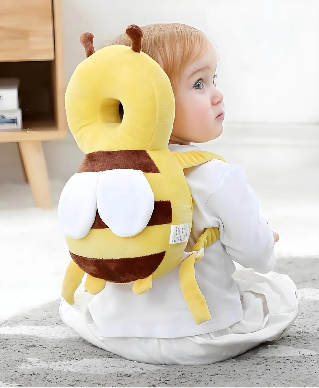 Baby wearing the bee backpack cushion while sitting